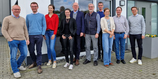 Fabian Kreutz (smart media), Jonathan Behm (Uni PB), Anna-Carina Zappe (smart media), Sara Schmidt (Wirtschaftsförderung), Thomas Höddinghaus (Stadt Menden), Johannes Weyer, Fabian Adelt (beide TU), Alessa Näpel, Matthias Thelen (beide Stadtwerke), Moritz Ostermann (Uni PB) stehen vor einer Fensterfront.