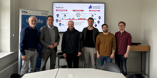 Professor Johannes Weyer, Christian Fronczak vom MUNV, Marlon Phillipp, Kay Cepera, Antonio Isopp und Sebastian Hoffmann (v.l.n.r.) stehen vor einem großen Monitor, auf welchem die Grundzüge des Ne.Mobil-Projekts aufgezeichnet sind.