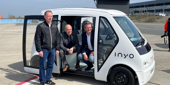 Das NeMo-Cab wird in Paderborn präsentiert. Marcus Zwick, Christoph Rüther und Thomas Tröster sitzen und lehnen sich an dem Taxi an.