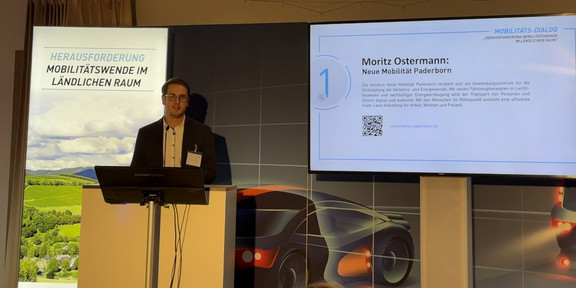 Moritz Ostermann steht hinter einem Rednerpult vor einem Banner auf dem "Mobilitätswende im ländlichen Raum" steht.